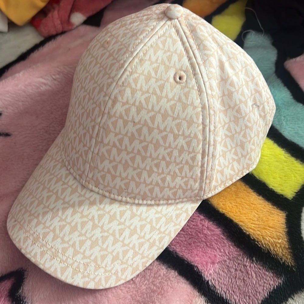 Michael kors pink hat with white MK pattern written all over it .